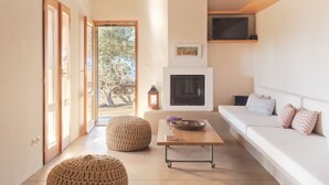 A modern living room with a fireplace, a sofa, and a coffee table. - A house in an olive grove with a unique view to the Aegean sea. (Tinos)
