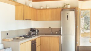 A modern kitchen with wooden cabinets, a stainless steel refrigerator, and a built-in oven. - A house in an olive grove with a unique view to the Aegean sea. (Tinos)