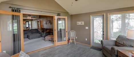 Un vaste espace de vie agrémenté d’un ventilateur de plafond, d’une porte-fenêtre coulissante donnant sur un balcon et d’un coin salon confortable.