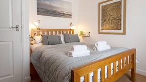 A neatly made bed with a striped bedspread, two bedside lamps, and a framed artwork above the bed. - 3 Victoria House, St Ives – Sleeps 4 – Sea Views (St Ives)