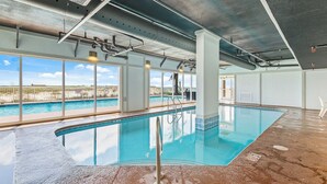 Ein Hallenbad mit freiem Blick auf Strand und Meer durch große Fenster.