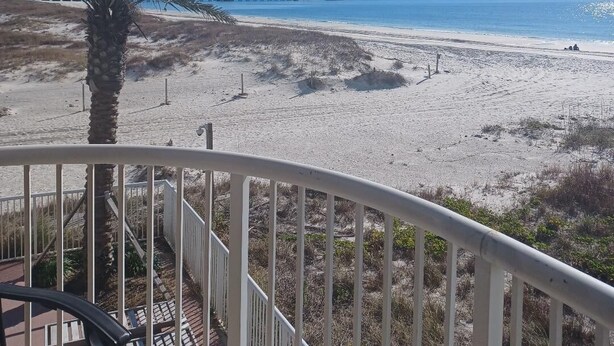Ein Strand mit einer Palme, einer Mole und einem Baukran im Hintergrund.