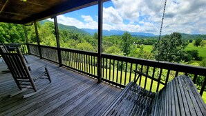 Eine Holzterrasse mit Blick auf eine grüne Landschaft und Berge.