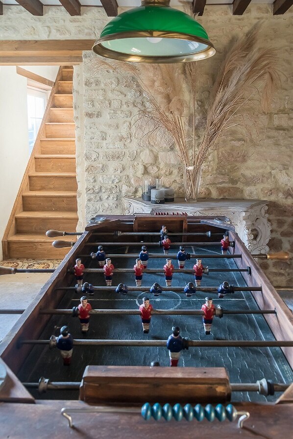 A foosball table in a room with stone walls and wooden beams.