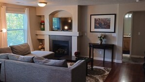 A living room with a fireplace, a sofa, a coffee table, and a dining area with a table and chairs. - Beautiful Condo in South Jordan Utah (South Jordan)