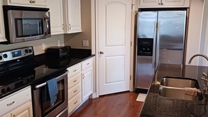 A modern kitchen with stainless steel appliances, white cabinetry, and a black countertop. - Beautiful Condo in South Jordan Utah (South Jordan)