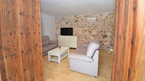 A living room with a stone wall, a television, a sofa, and a coffee table.