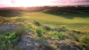 A golf course with rolling hills and a clear sky.