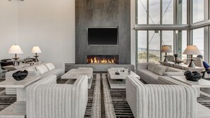 A modern living room with a fireplace, large windows, and contemporary furniture.