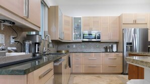 A modern kitchen with light wood cabinets, stainless steel appliances, and a granite countertop. - Lands Fine Art Gallery  (Hollywood)