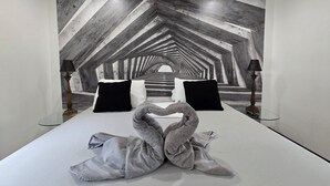 A bed with a unique wall mural, two black pillows, and two lamps. - Lands Fine Art Gallery  (Hollywood)