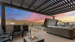 Una terrazza esterna con un focolare, un'area salotto e un barbecue.