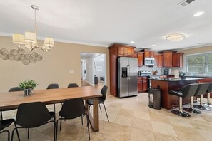 A modern kitchen with a central island, stainless steel appliances, and a dining area with a wooden table and chairs.