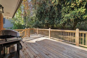 A wooden deck with a barbecue grill, surrounded by trees and a wooden fence. - Stylish Stone Mountain home, sleeps 8 (Stone Mountain)