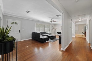 A spacious living room with hardwood flooring, a sectional sofa, a coffee table, and a potted plant. - Stylish Stone Mountain home, sleeps 8 (Stone Mountain)