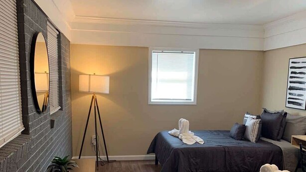 A hotel room with two beds, a standing lamp, a mirror, and a window. - Stylish Stone Mountain home, sleeps 8 (Stone Mountain)