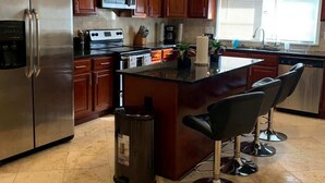 A modern kitchen with wooden cabinets, stainless steel appliances, and a bar area with stools. - Stylish Stone Mountain home, sleeps 8 (Stone Mountain)