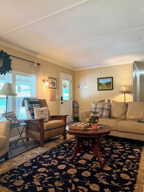 A living room with a sofa, armchair, coffee table, and a floral carpet.