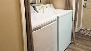 A laundry room with two white washing machines, a drying rack, and a door with a 'No Smoking' sign. - Rustic Countryside Cottage (Cleveland)