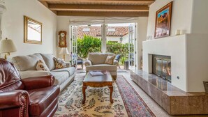A living room with a fireplace, leather sofa, armchairs, and a coffee table. - Enjoy the Beauty of Downtown Santa Barbara Walk Everywhere! (Santa Barbara)