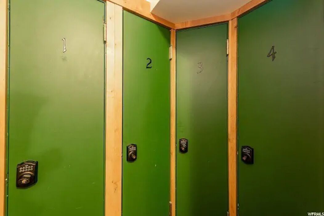 Quattro armadietti verdi in fila, numerati da 1 a 4, ciascuno con una serratura e una chiave.