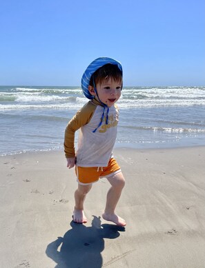 A child on a sandy beach with waves in the background. - Luxurious Home w/ Elevator. Private Pool. Close Walk to the Beach. Very Clean. (South Padre Island)