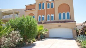 Un edificio residenziale a due piani, con facciata beige, diverse finestre e un portone garage bianco.