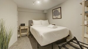 Een netjes opgemaakte slaapkamer met een bed, nachtkastje en een wandplank.