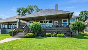 A two-story house with a covered porch, a staircase, and a well-maintained lawn. - Casa KK | Luxe Lakefront 4BR/3BA w/ Views & Dock (Gun Barrel City)