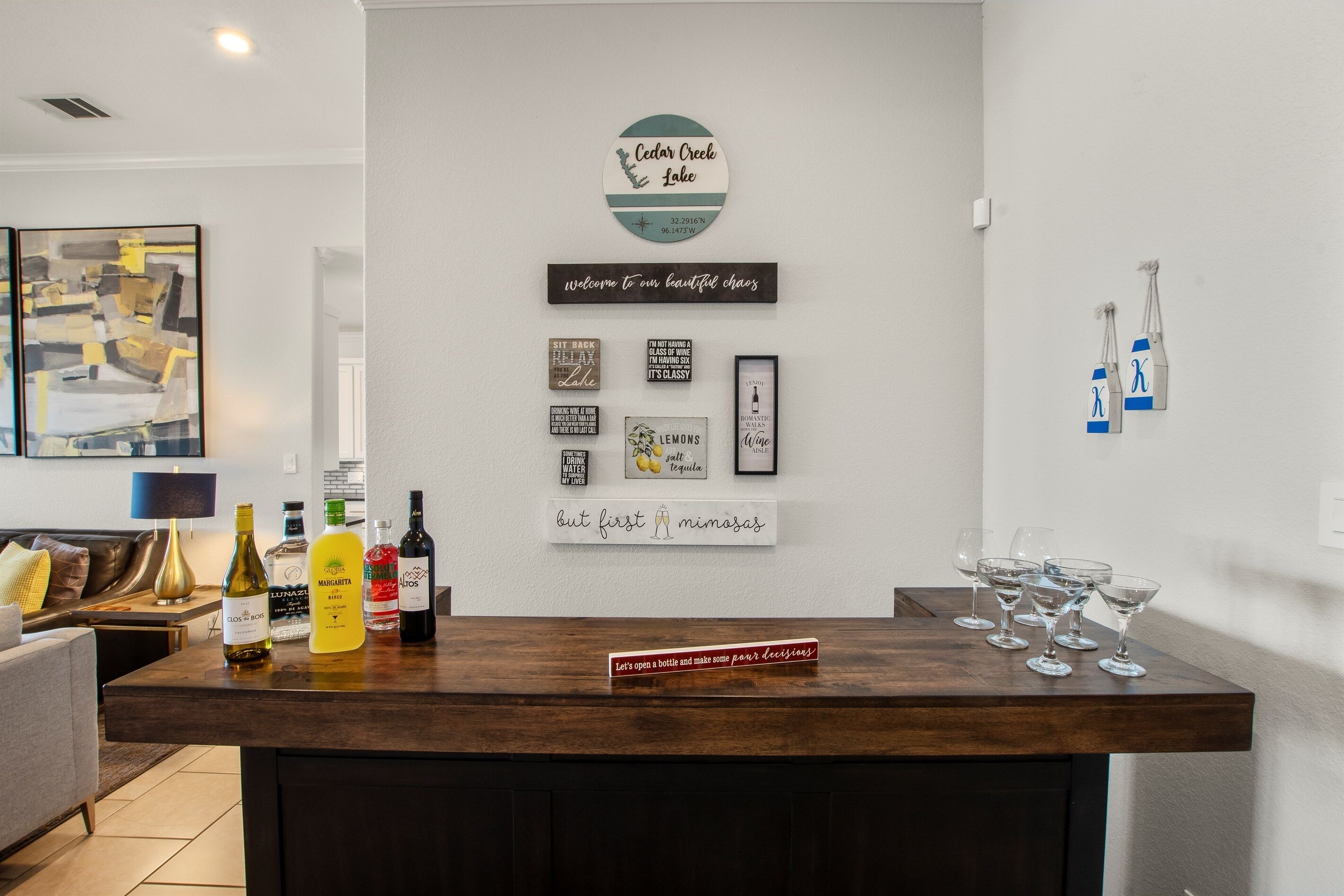 Een bar met een houten toonbank, diverse flessen en ingelijste borden aan de muur.