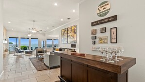 A spacious living area with a wooden reception desk, large windows, and a view of the ocean. - Casa KK | Luxe Lakefront 4BR/3BA w/ Views & Dock (Gun Barrel City)