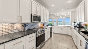 A modern kitchen with white cabinetry, a black stove, and a microwave. - Casa KK | Luxe Lakefront 4BR/3BA w/ Views & Dock (Gun Barrel City)