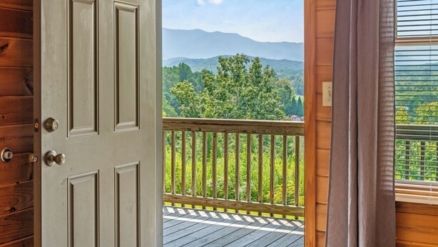 A wooden door leading to a balcony with a view of mountains and trees. - Smokin Sunrise Cabin (Cosby)