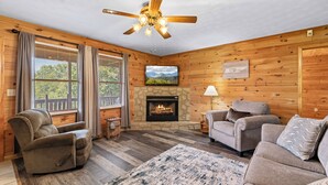 A cozy living room with a fireplace, wooden walls, and comfortable seating. - Smokin Sunrise Cabin (Cosby)