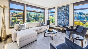 Una sala de estar moderna con un ventanal grande, un sofá, una mesa de centro y una silla.