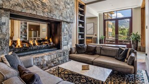 Una sala de estar moderna con chimenea de piedra, un sofá, una mesa de centro y vistas al exterior.