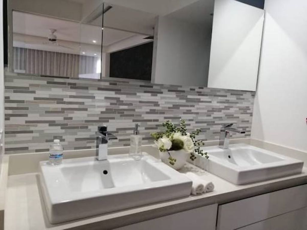 Une salle de bain moderne avec deux lavabos, un miroir et un mur recouvert de carreaux.