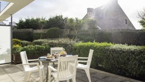 A patio with a table and chairs, surrounded by greenery and a stone wall. - Résidence Villa Cassandre by Interhome (Quiberon)