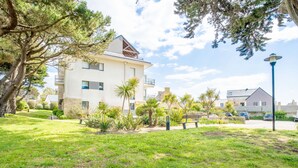 A residential building with a modern design, surrounded by a well-maintained lawn and various plants. - Résidence Villa Cassandre by Interhome (Quiberon)