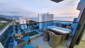 A balcony with wicker furniture and a glass table, overlooking a cityscape and the sea. - Beachfront Family Escape | 3BR Samaria Club! (Santa Marta)