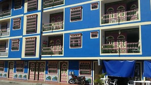 A multi-story building with balconies, a motorcycle parked outside, and outdoor seating. - an anchor for the soul (Guatape)