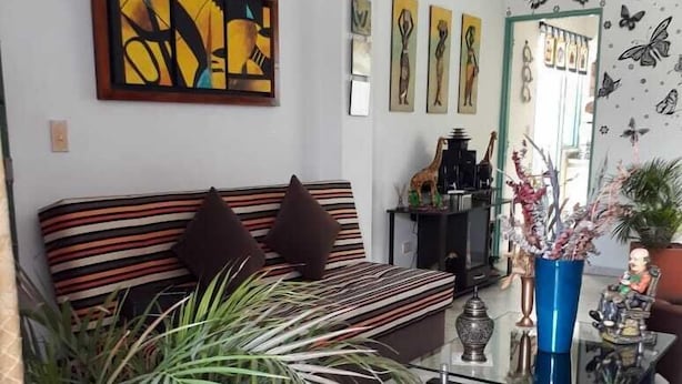 A living room with a striped sofa, a glass coffee table, and a large potted plant. - an anchor for the soul (Guatape)