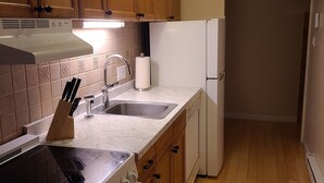 Une cuisine avec des meubles de rangement en bois, une cuisinière, un évier et un réfrigérateur.