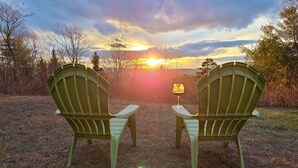 Deux fauteuils Adirondack placés face à face, avec un coucher de soleil en arrière-plan.