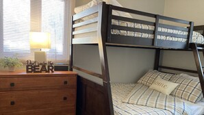 Un lit superposé avec une couverture à carreaux et un oreiller orné du mot « chez soi ».
