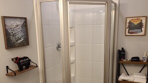 Une salle de bain avec une douche, des toilettes et des étagères où sont rangées les serviettes.