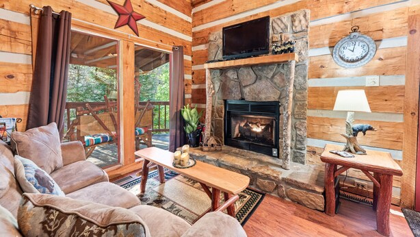 A cozy cabin interior with a stone fireplace, wooden walls, and a comfortable seating area. - Just 10 minutes from GSM National Park, 2 BR Log Cabin with Hot Tub & Firepit (Pigeon Forge)
