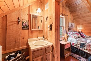 Cozy cabin-style room with a wooden ceiling, large mirror, and comfortable bed.