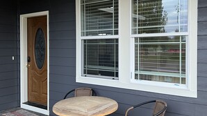 A dark grey house with a wooden front door, two wicker chairs, and a small round table. - Large Independence House for Families & Groups (Independence)