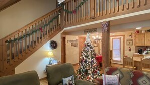 Ein gemütliches Blockhaus-Interieur mit einer Holztreppe, einem Weihnachtsbaum und einem Essbereich.